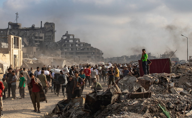 Displaced Palestinians carry relief parcels along Rashid Street, west of Gaza City